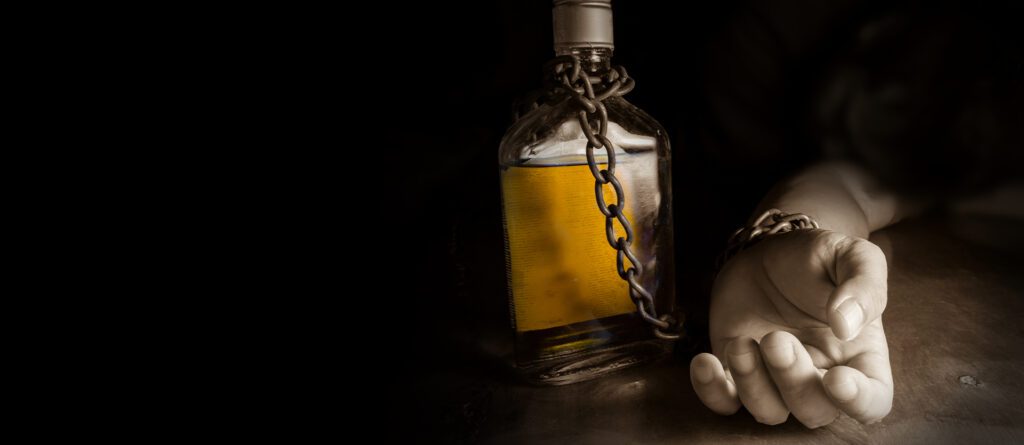 An image of someone chained to a bottle of alcohol, showing the struggles of substance abuse disorders and the concept of addiction vs. dependence