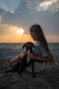 An image of a girl with her dog at the beach, showing the benefits of animal assisted therapy 