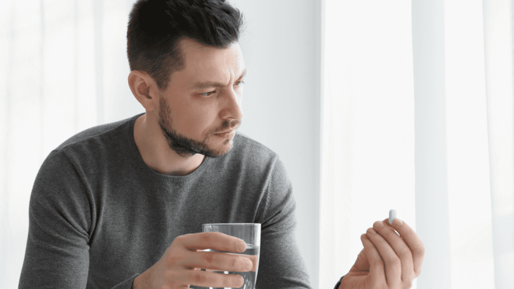 a man hold a drink in his hand and a pill to represent oxycodone and alcohol. 