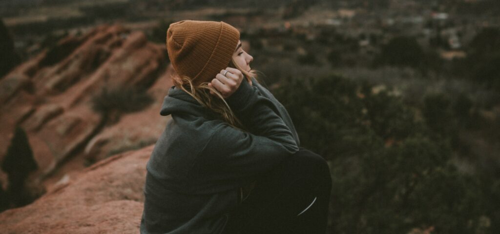 a woman sits on a large rocky hill to represent quitting fentanyl cold turkey