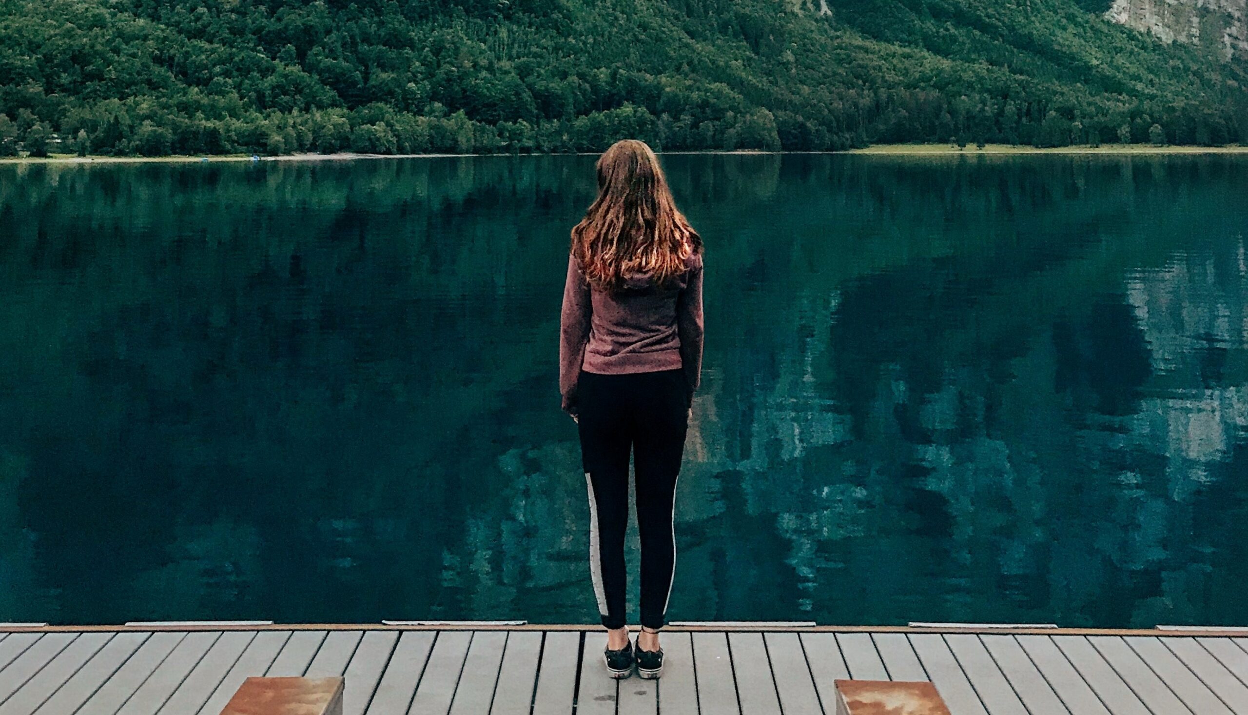 A woman is standing on a dock looking out at a lake to represent the question: Is cocaine a stimulant?