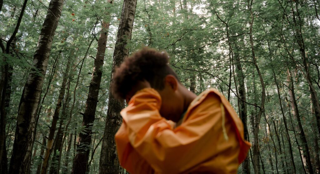 a person is standing with their head in their hands to represent the dangers of mixing oxycodone and alcohol.