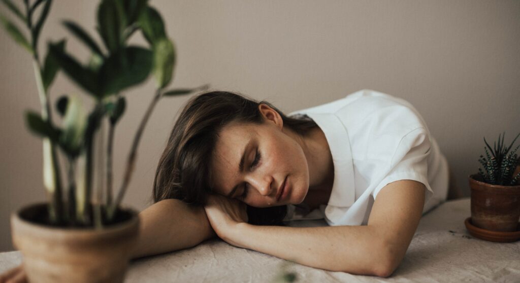 A woman lays her head on a table to represent the long-term effects of cocaine use.