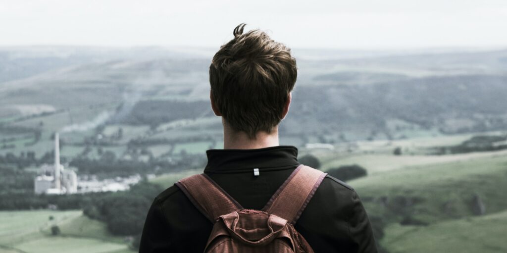 A man stands on a hillside looking out a the scenery to represent signs of alcohol withdrawal.