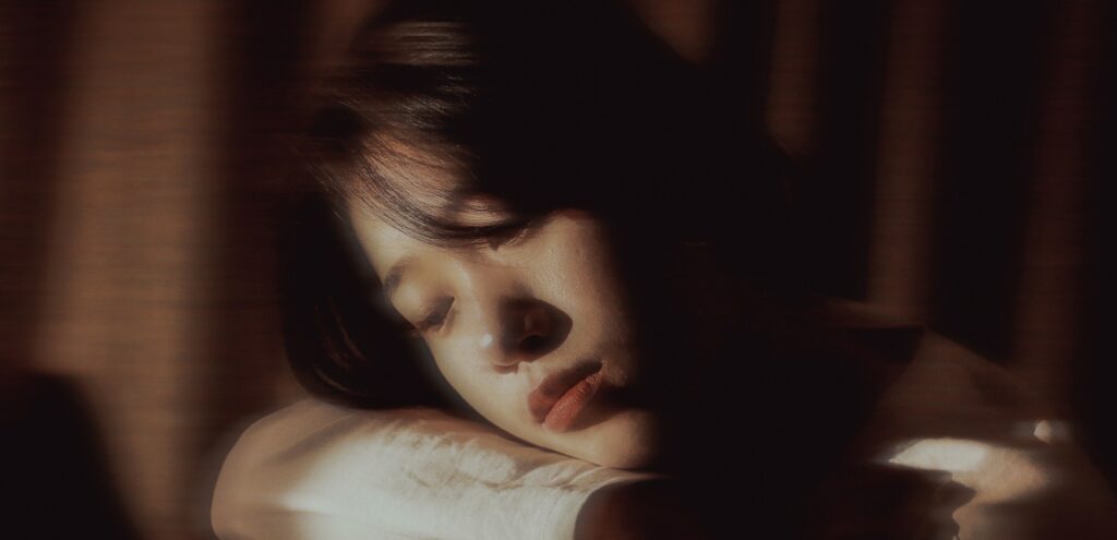 A woman lays her head on her crossed arms to represent bipolar and drinking