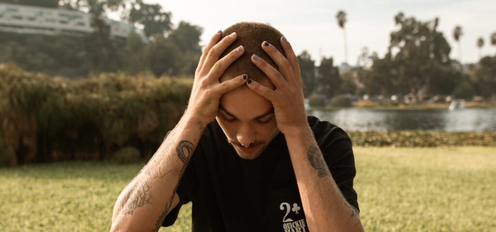 A man with his head in his hands representing side effects of adderall.