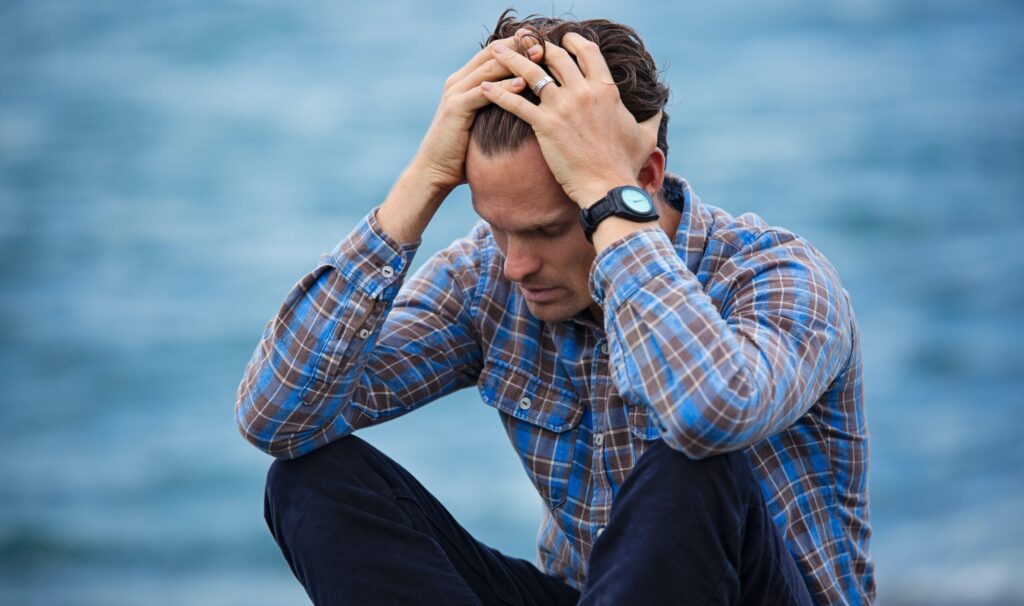 image of man head in hands representing symptoms of overdose