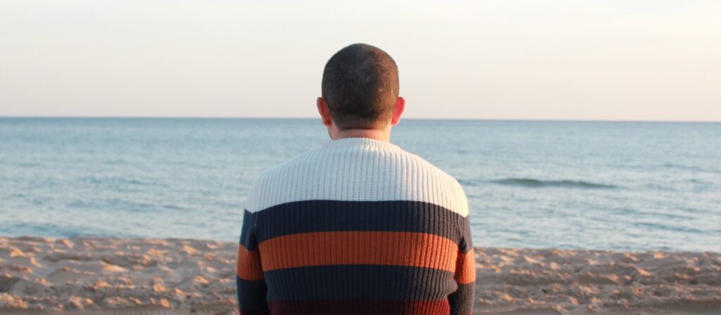 A man looks out at the ocean representing: does drinking alcohol cause hair loss?