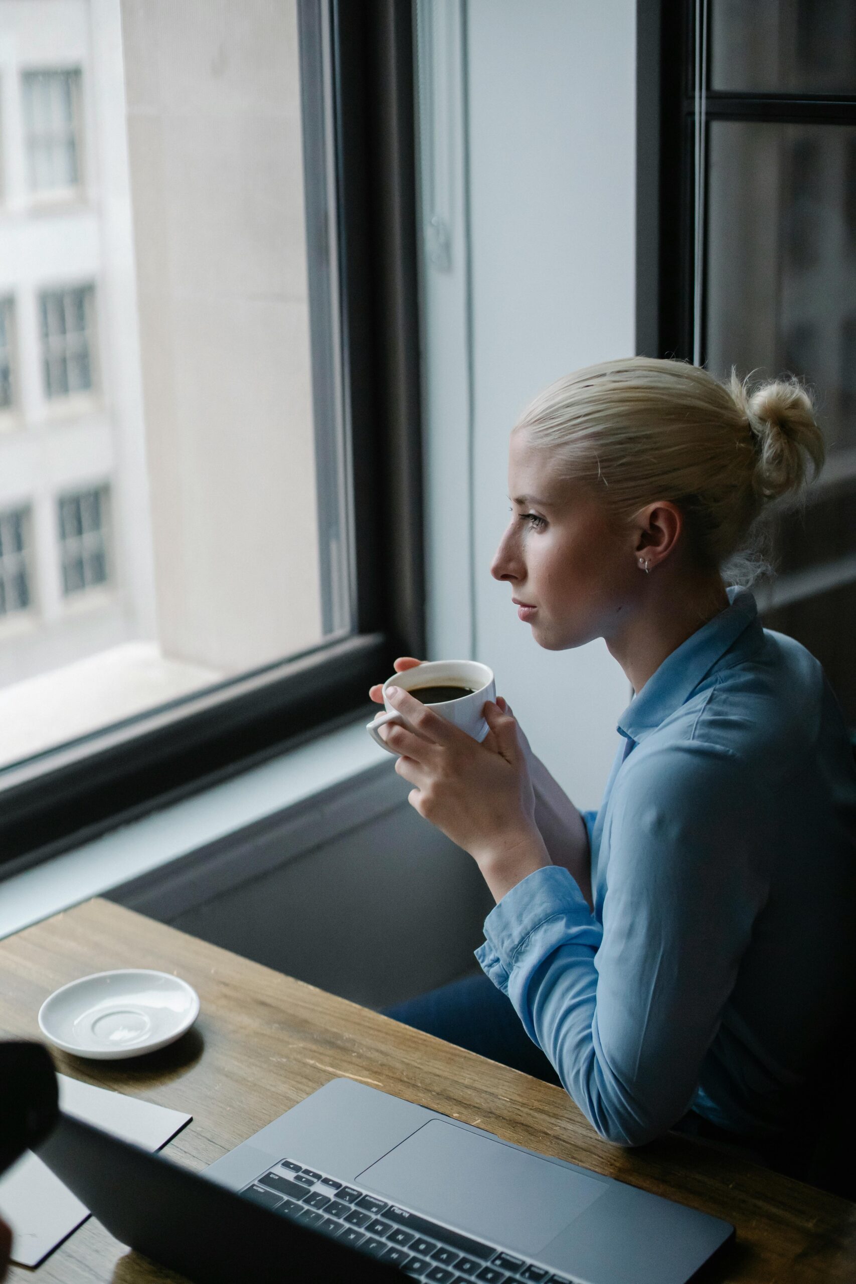 A woman drinking coffee, gazing out the window, wondering if Lexapro addiction is possible
