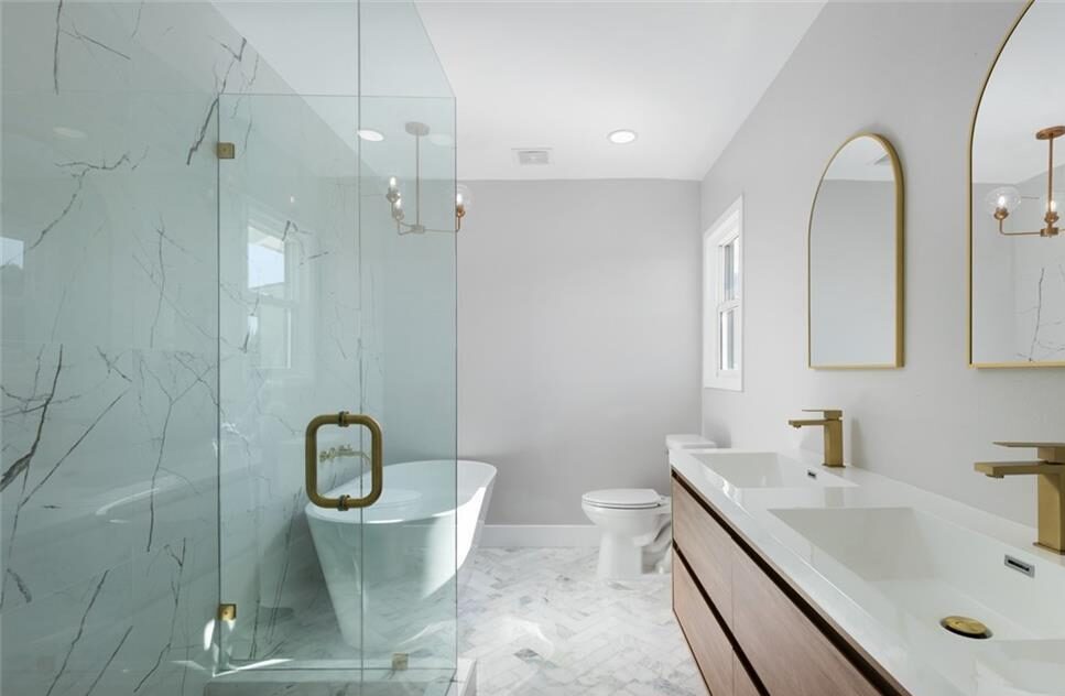 Bathroom with a standing shower, bathtub to the side, double sink, and a toilet