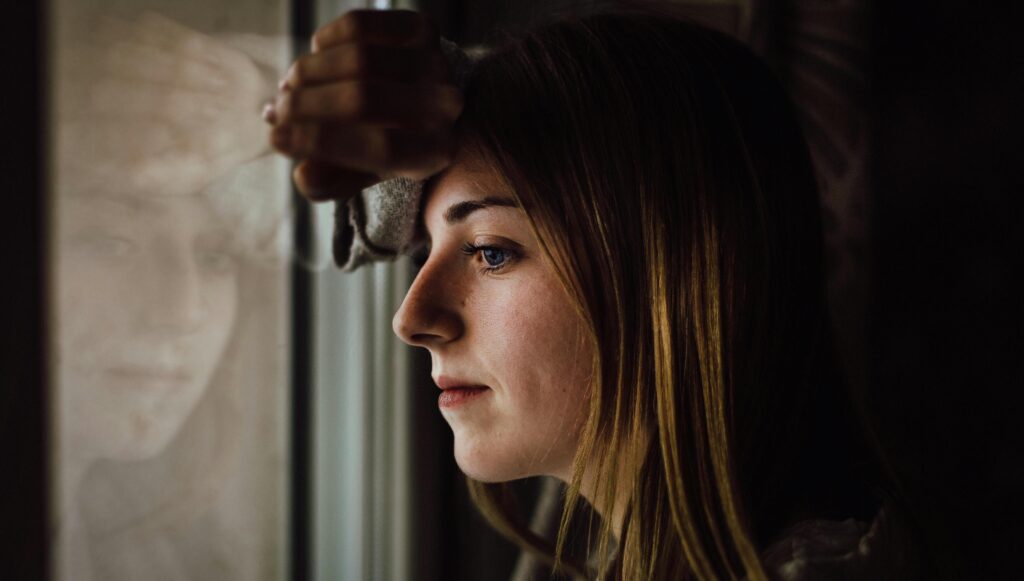 woman leaning against window representing how to break a trauma bond