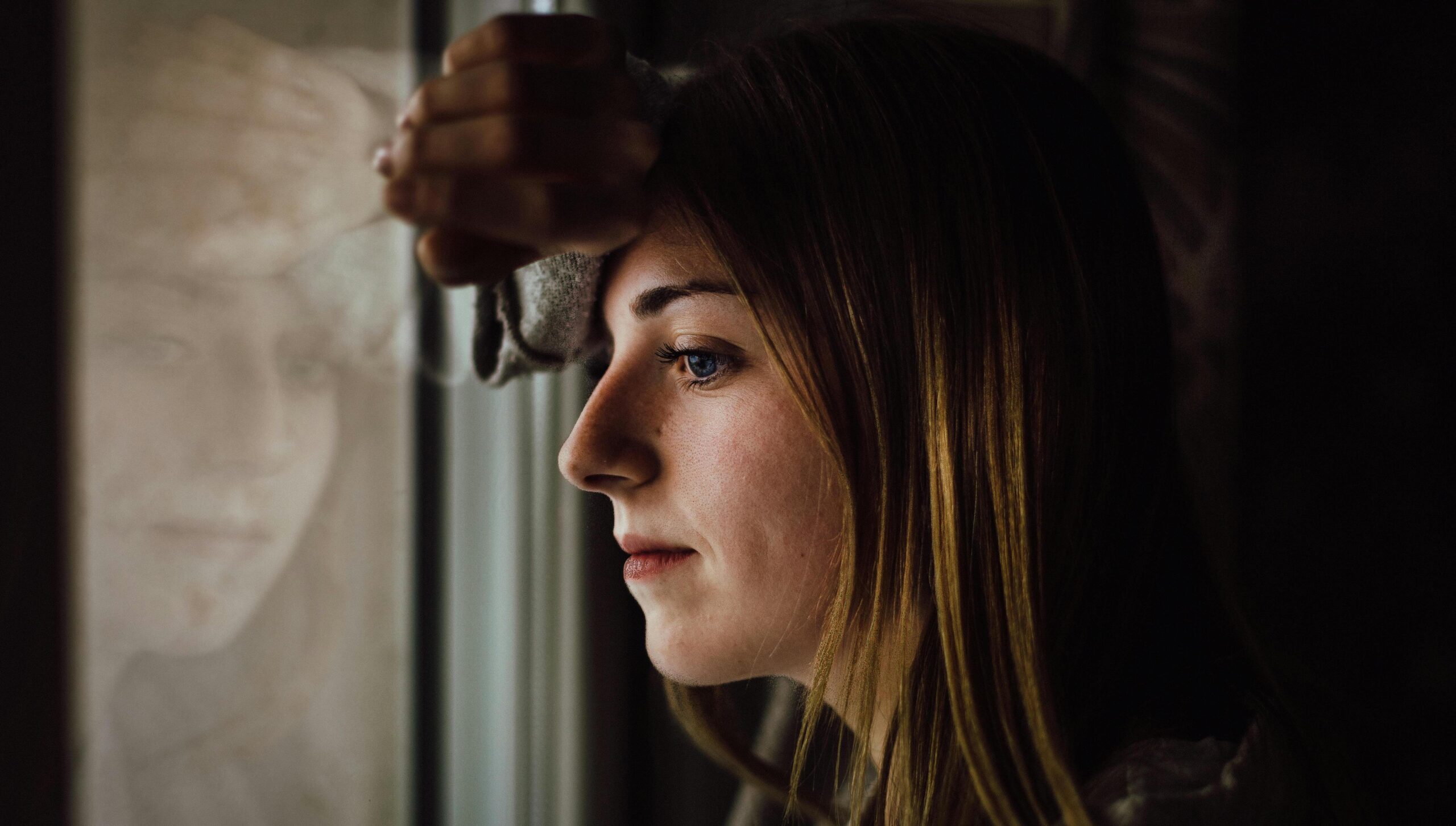 woman leaning against window representing how to break a trauma bond